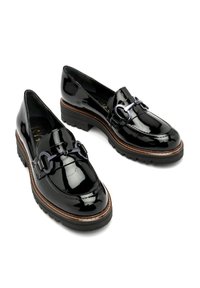 Mocassins en cuir verni noir avec semelles en caoutchouc épaisses et détail métallique en mors de cheval sur le dessus, présentés sur un fond blanc.