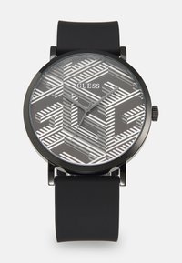 Schwarze Uhr mit einem grau gemusterten Zifferblatt in geometrischem Design, mit silbernen Akzenten, einem runden Gehäuse und einem mattschwarzen Silikonarmband.