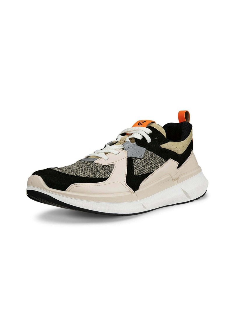 Sport-Sneaker mit einem atmungsaktiven Obermaterial aus Mesh in Grau, Schwarz und Creme, einer kräftigen weißen Sohle und einem orangefarbenen Akzent an der Ferse.