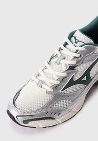 Mesh and synthetic running shoe in white, silver, and green. Features textured upper, cushioned collar, and contrasting sole design.