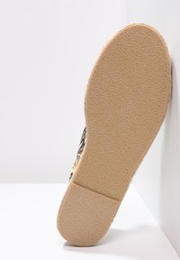 Guma podešve s texturovaným gripem, představující vzorovaný svršek s květinovým designem v různých barvách na tmavém pozadí.