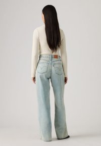 Φαρδιά τζιν παντελόνια σε ανοιχτό μπλε χρώμα με ψηλή μέση, κατασκευασμένα από τζιν ύφασμα. Διαθέτουν πίσω τσέπες και δερμάτινη ετικέτα με λογότυπο στη μέση.