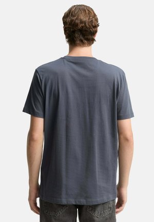 Grey cotton t-shirt with a circular neckline, short sleeves, and a relaxed fit, featuring a smooth texture and minimal detailing on the back.