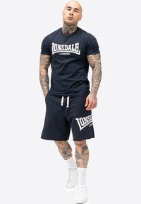 Mørkeblå bomulds t-shirt og matchende shorts med hvid "LONSDALE LONDON" branding, der har rund hals, korte ærmer og snøre.