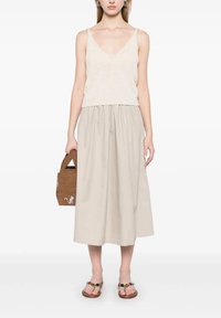 Top in maglia beige, gonna midi fluida beige, borsa intrecciata marrone e sandali colorati con decorazioni. Outfit semplice e casual con tessuti morbidi.