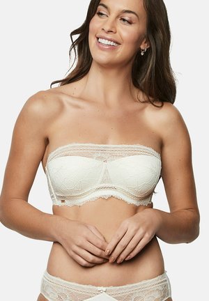 Soutien-gorge blanc sans bretelles avec un design en dentelle florale, des bords festonnés et une texture lisse. Le vêtement comprend un rôle à baleines pour le maintien.