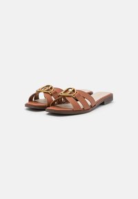 Braune Leder-Sandalen mit offenem Zehenbereich, ausgestattet mit drei gestreiften Bändern und einer goldenen Schnalle an der Vorderseite. Flache Sohle.