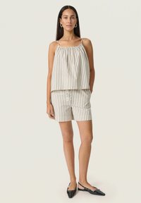 Haut sans manches à rayures avec encolure froncée, accompagné d'un short assorti, le tout en beige clair et rayures verticales foncées. Ballerines noires en vernis.