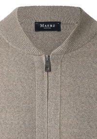Brauner Strickpullover mit hohem Kragen, mit einem Frontreißverschluss und Rippendetails. Das Etikett trägt "Maerz Muenchen." Weicher Stoff.