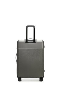 Hard-shell suitcase in dark gray, featuring a textured surface, retractable handle, and four wheels for mobility.