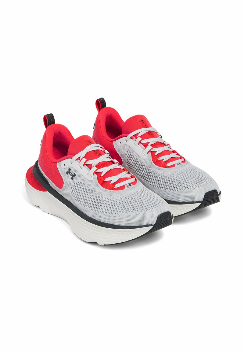 Zapatillas deportivas grises y rojas con parte superior de malla, mediado acolchado blanco y suela negra. Cuenta con cordones redondos y una lengüeta.