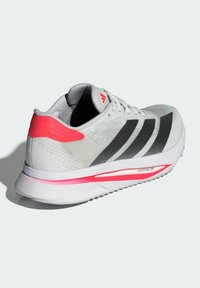 White athletic shoe with black stripes and a pink heel accent, featuring a textured upper, cushioned sole, and lightweight design.