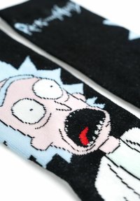 Calzini neri con una grafica di un personaggio dei cartoni animati sorpreso, con capelli azzurri chiari, pelle rosa e un camice da laboratorio bianco e nero.