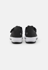 Schwarze Sportschuhe mit strukturiertem Obermaterial, Klettverschluss, weißer Zwischensohle und schwarzem Gummiaußensohle. Mit einem Globus-Logo an der Ferse.
