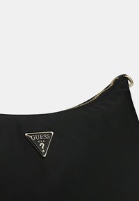 Borsa a spalla nera in nylon con logo metallico triangolare e testo "GUESS U.S.A.", chiusura con zip e texture liscia.