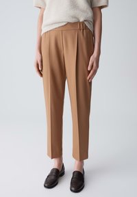 Braune, maßgeschneiderte Hosen aus strukturiertem Stoff mit hohem Bund, scharfen Falten und cropped, geraden Beinen.