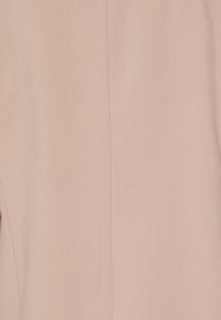 Tessuto rosa chiaro con una consistenza liscia e una leggera lucentezza. Presenta una cucitura centrale che corre verticalmente lungo il centro.