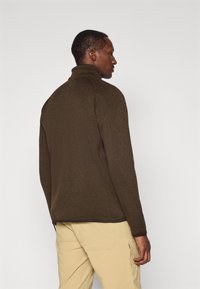 Brown fleece pullover with a high collar and long sleeves. Smooth texture, flat-locked seams, and a straight hem.
