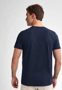 Námořnická modrá tričko s krátkým rukávem a kulatým výstřihem. Vyrobené z hladké bavlněné látky, má jednoduchý, nenáročný design.