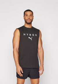 Black sleeveless athletic shirt with white "HYROX" text and Puma logo. Soft fabric, crew neckline, worn with dark shorts.