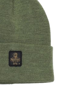 Beanie verde lavorato a maglia in tessuto, con risvolto e una toppa rettangolare nera con logo di un cane e nome del marchio.
