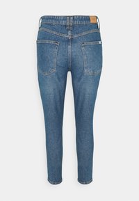 Tmavě modré džíny z denimu s přiléhavým střihem, styl pěti kapes a mírně zúženou nohavicí, ukazující klasický vzor šití.