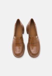 Paire de mocassins en cuir marron poli avec bouts carrés arrondis et petits talons en bois, vus de dessus sur un fond blanc.