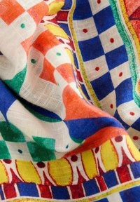 Multicolored fabric with a checkered pattern in red, blue, green, and yellow, featuring an intricate border design and sheer texture.