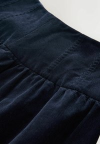 Țesătură de catifea cord cu o nuanță marină, cu talie gathered și nervuri verticale. Prezintă o textură netedă și o colorare consistentă pe întreaga suprafață.