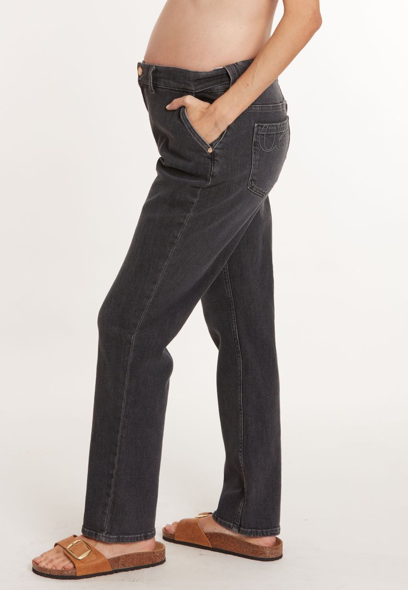 Jeans de maternité gris foncé avec une coupe droite, comportant des poches avant et une taille lisse. Portés avec des sandales marron.