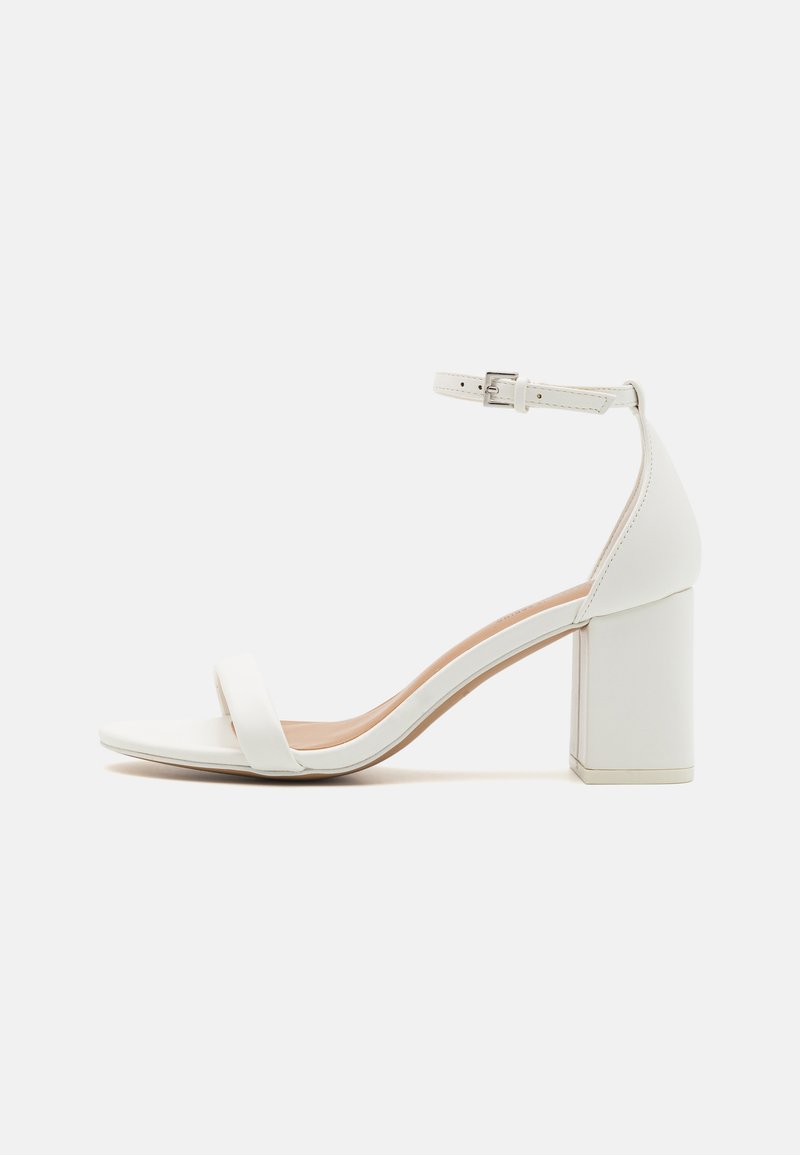 White block-heel sandal featuring smooth synthetic material, wide strap across the toe, adjustable ankle strap, and a textured insole.