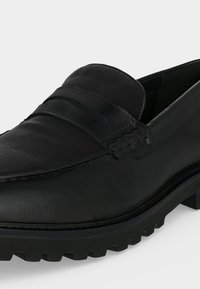 Μαύρο δερμάτινο μοκασίνι με λουράκι penny, λεπτομερές ράψιμο και χοντρή σόλα με πέλμα για επιπλέον πρόσφυση και ανθεκτικότητα.