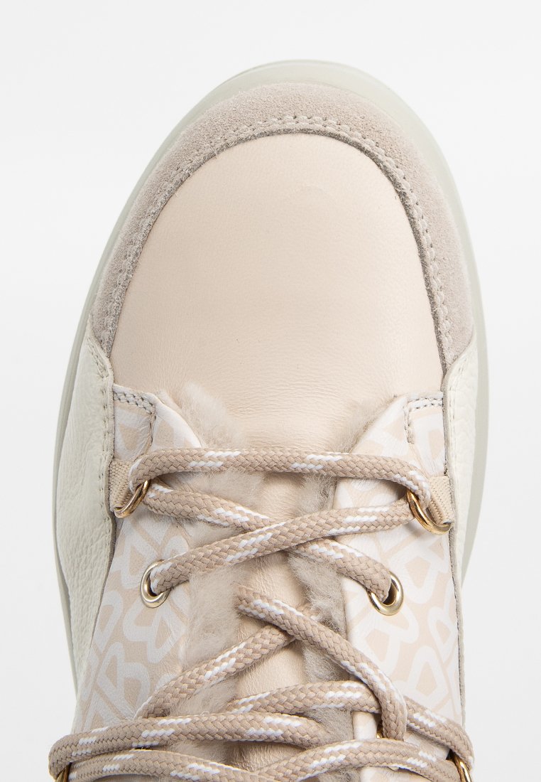 Sneaker z zaokrąglonym noskiem, wykonany z kremowej skóry, z akcentami z brązowego zamszu oraz wzorzystą tkaniną. Jasnobrązowe sznurówki i złote elementy.