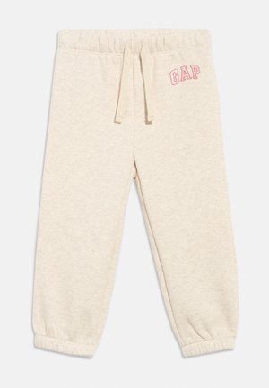 Pantaloni della tuta per bambini color beige chiaro con vita e polsini elastici, coulisse frontale e logo "GAP" rosa sull'anca sinistra.
