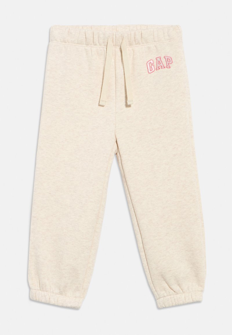 Svetlo béžové detské tepláky s elastickým pásom a lemami, šnúrkou vpredu a ružovým logom "GAP" na ľavom boku.