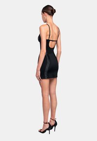Schwarzes Minikleid mit dünnen Trägern, ausgestattet mit einem runden Rückenausschnitt und gerafften Seitendetails. Glatter Stoff mit passender Silhouette.