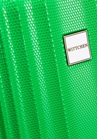 Zelený kufr s texturovaným vzorem včelí plástve, s výrobním štítkem stříbrné barvy, na němž je nápis "WITTCHEN". Materiál vypadá leskle a odolně.