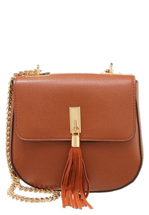 Brun læder crossover taske med guld kæderem og guldlås med en matchende læderkvast på en hvid baggrund.