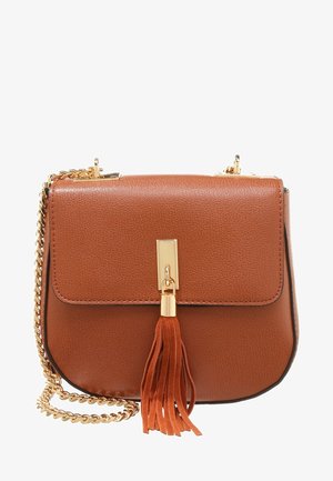 Bolso cruzado de cuero marrón con correa de cadena dorada y cierre dorado que presenta un tassel de cuero a juego sobre un fondo blanco.