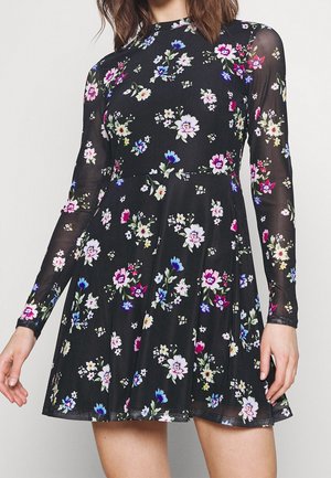 Robe longue à manches longues à motif floral avec un fond noir et des fleurs multicolores. Le tissu est léger et la jupe est évasée.