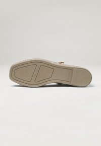 Suela de alpargata beige con una superficie de goma texturizada, que presenta una forma ancha y plana y un diseño simple y minimalista.
