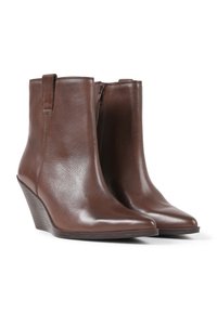 Botas de piel marrón hasta el tobillo con punta afilada y tacón en cuña. Presentan una textura suave y un cierre lateral con cremallera.