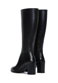 Bottines noires en cuir jusqu'au genou avec une texture lisse, une pointe carrée et un talon épais. Présente une couture minimale et un design épuré.