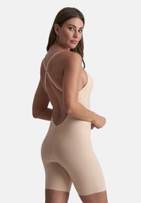 Body nudo con un design aderente, spalline incrociate sottili e schiena scoperta. Il materiale appare liscio con cuciture minime e una lunghezza delle gambe corta.