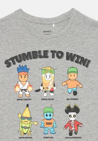 Seks tegneseriefigurer på en grå skjorte under "SNUBL FOR Å VINNE!": Sensei Firefist, Cereal Killer, Mr. Stumble, Super Banana, Robot Guy, Captain Noheart.