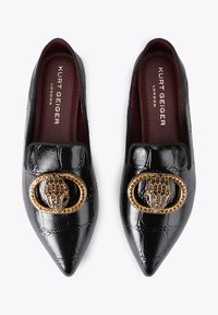 Mocassins noirs embossés effet crocodile avec bout pointu. Ornements décoratifs dorés en forme de main. Doublure intérieure bordeaux, marque visible.