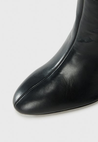 Black leather ankle boot with a pointed toe, smooth texture, seam detailing, and a sleek, streamlined design.