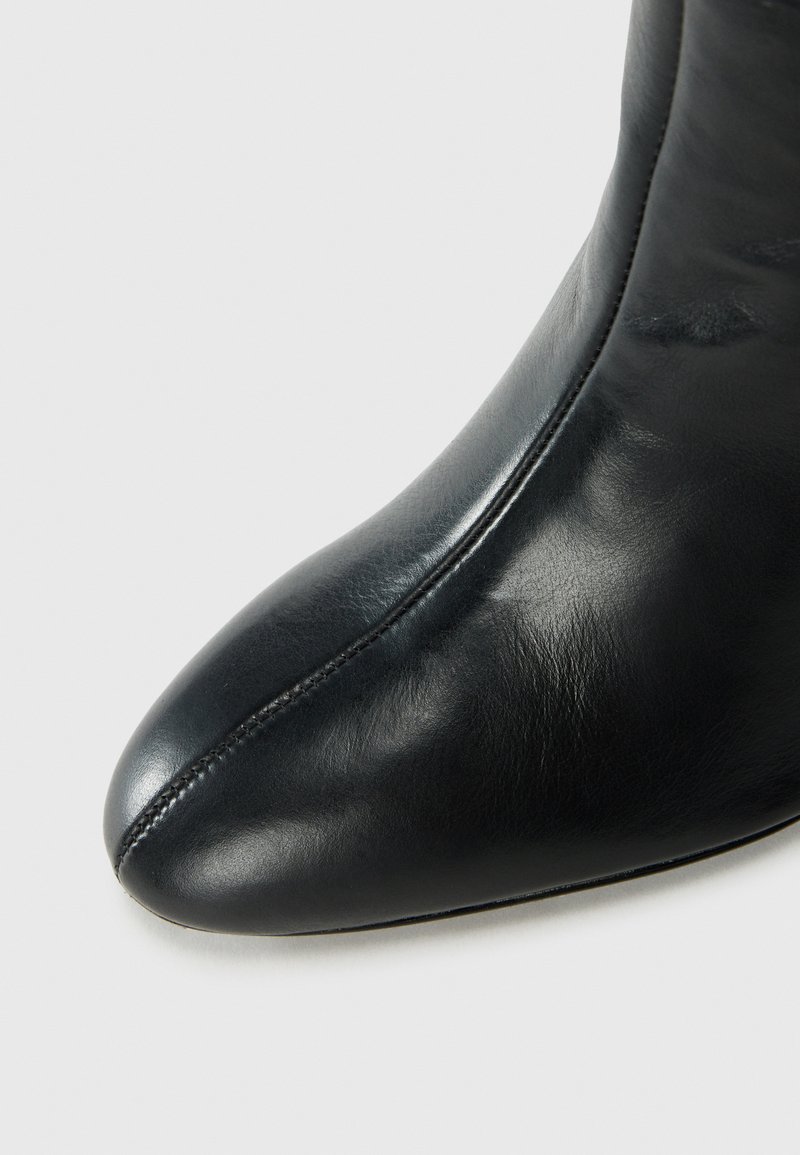 Schwarze Leder-Ankle-Boots mit spitz zulaufender Zehe, glatter Textur, Nahtdetails und einem eleganten, stromlinienförmigen Design.