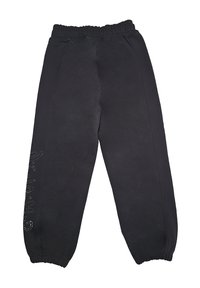 Pantaloni tuta neri in pile con vita e polsini elasticizzati, caratterizzati da piccole decorazioni di strass che formano una parola sulla gamba sinistra.