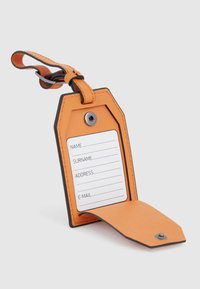 Oranje leren bagagelabel met een zwarte rand, voorzien van een blanco informatietaart voor naam, achternaam, adres en e-mail. Wordt geleverd met een riem.